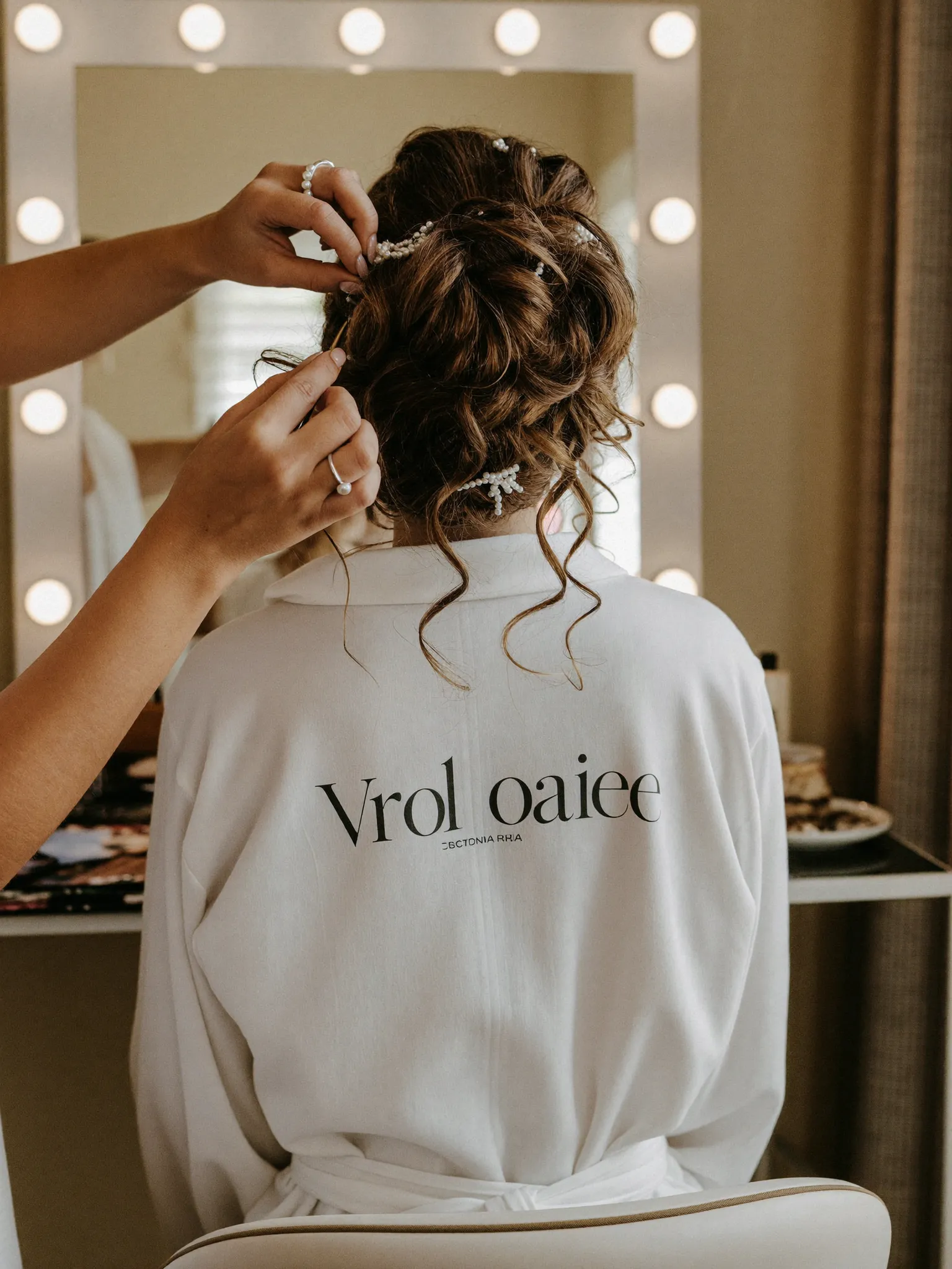 Bridal updo being styled at a vanity mirror